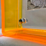 Close-up of magnetic corner screw on amber yellow translucent acrylic display block.