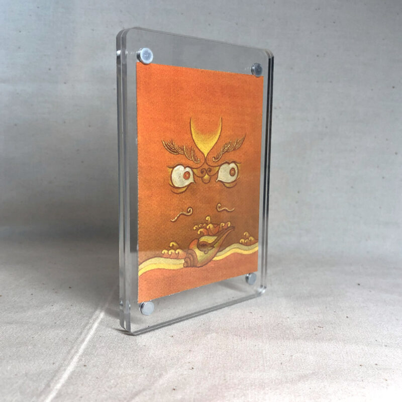 Side-angle view of freestanding clear acrylic block displaying Yellow Jambhala line art.