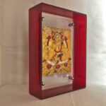 Side perspective of Yellow Jambhala Thangka print inside a red translucent acrylic display frame.