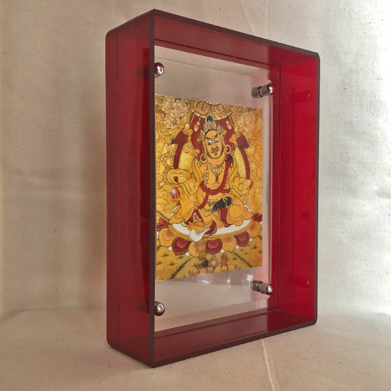 Side perspective of Yellow Jambhala Thangka print inside a red translucent acrylic display frame.