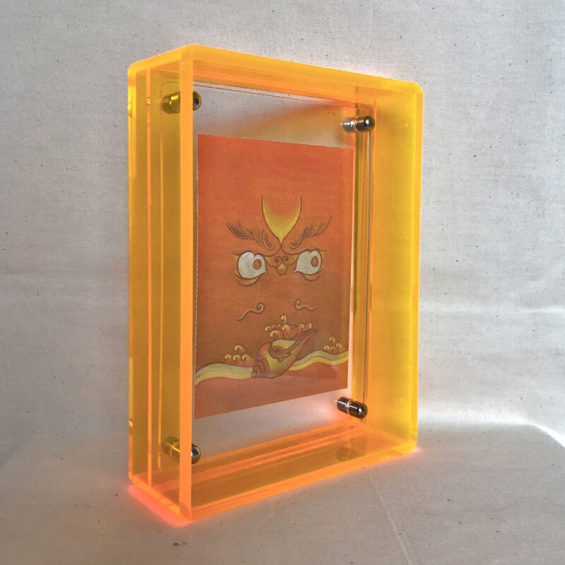Side perspective of yellow Jambhala Buddha Eyes art inside a yellow translucent acrylic frame.