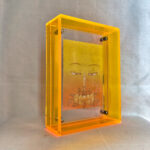 Side perspective of yellow Manjushri Buddha Eyes art inside a yellow translucent acrylic frame.