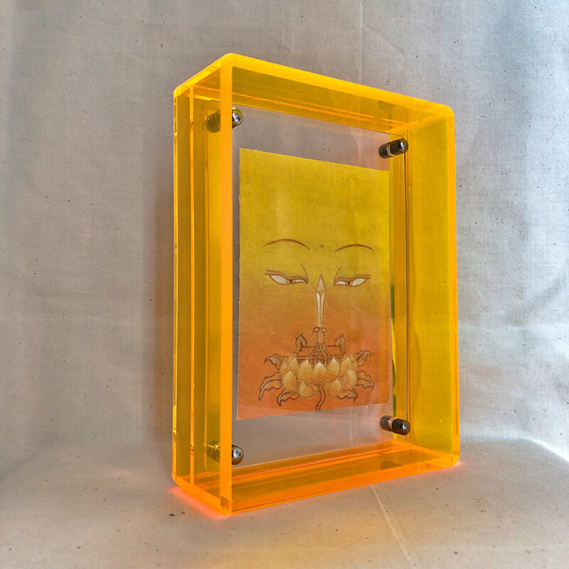 Side perspective of yellow Manjushri Buddha Eyes art inside a yellow translucent acrylic frame.