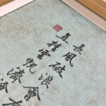 Close-up of Xingzhuo Chinese calligraphy brush strokes and red seal stamp on fine art textured paper