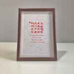 Frontal view of A4 red paper Chinese wedding calligraphy print in dark wood frame on clean desk