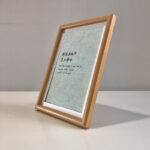 Side perspective view of A4 natural wood framed serene Chinese calligraphy print on tabletop