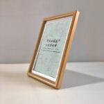 Side perspective view of A4 natural wood framed Chinese calligraphy print on tabletop