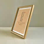 Side perspective view of A4 wooden framed calligraphy print on tabletop