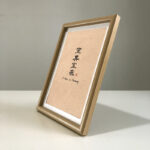 Side perspective view of A4 wooden framed home harmony print on tabletop