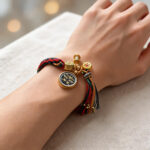 Black Padmasambhava Buddha Eye pendant bracelet with red and black tassel details on wrist.