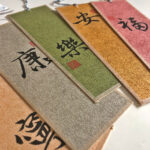 Close-up angled view of stacked colorful Chinese calligraphy bookmarks featuring auspicious character brushwork.