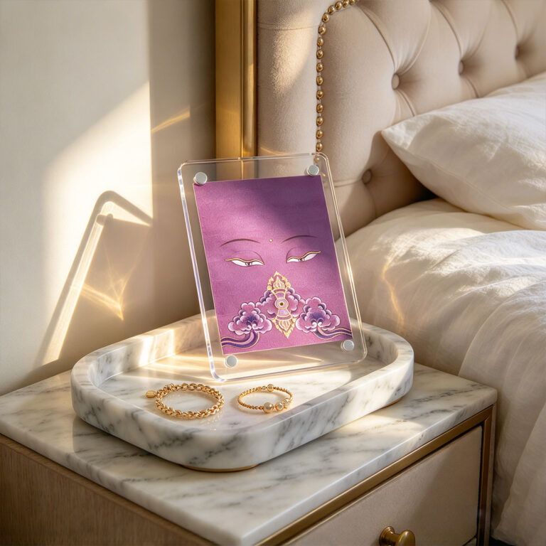A purple Buddha Eyes acrylic pocket block displayed on a white marble tray with gold jewelry in a sunlit bedroom.