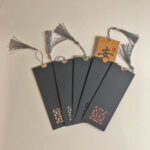 Chinese calligraphy blessing bookmarks displayed with black paper protective sleeves featuring laser-cut cutouts.
