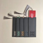 Chinese calligraphy bookmarks shown with black protective paper sleeves featuring intricate laser-cut cutouts.