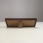 Side angle of calligraphy desk display showing foldable frame stand on white tabletop.