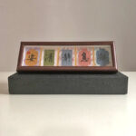 Handwritten 5-character Zen calligraphy display frame elevated on a black gift box.