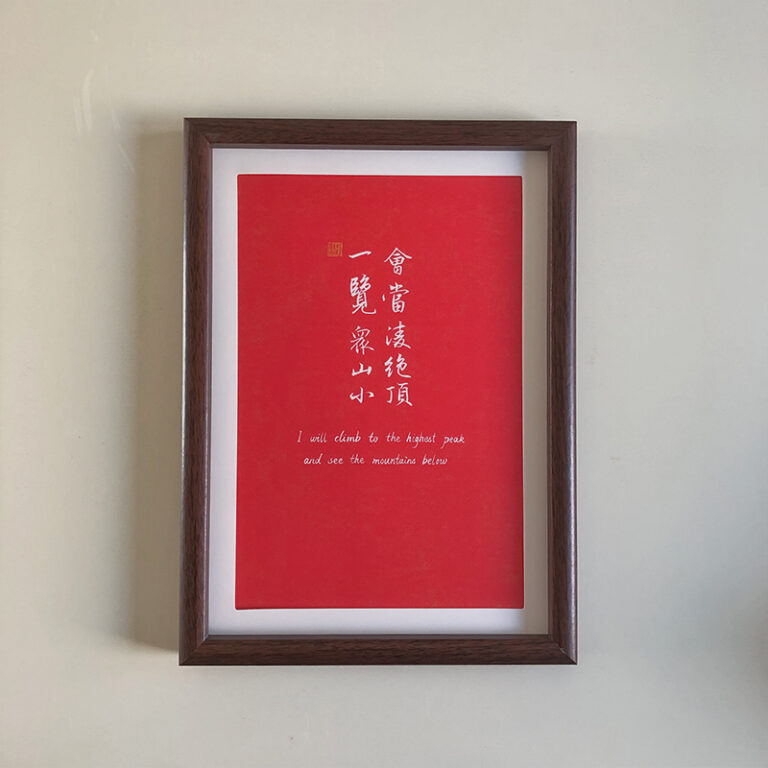 A4 framed red paper Chinese calligraphy art print with dark wood frame hanging on wall