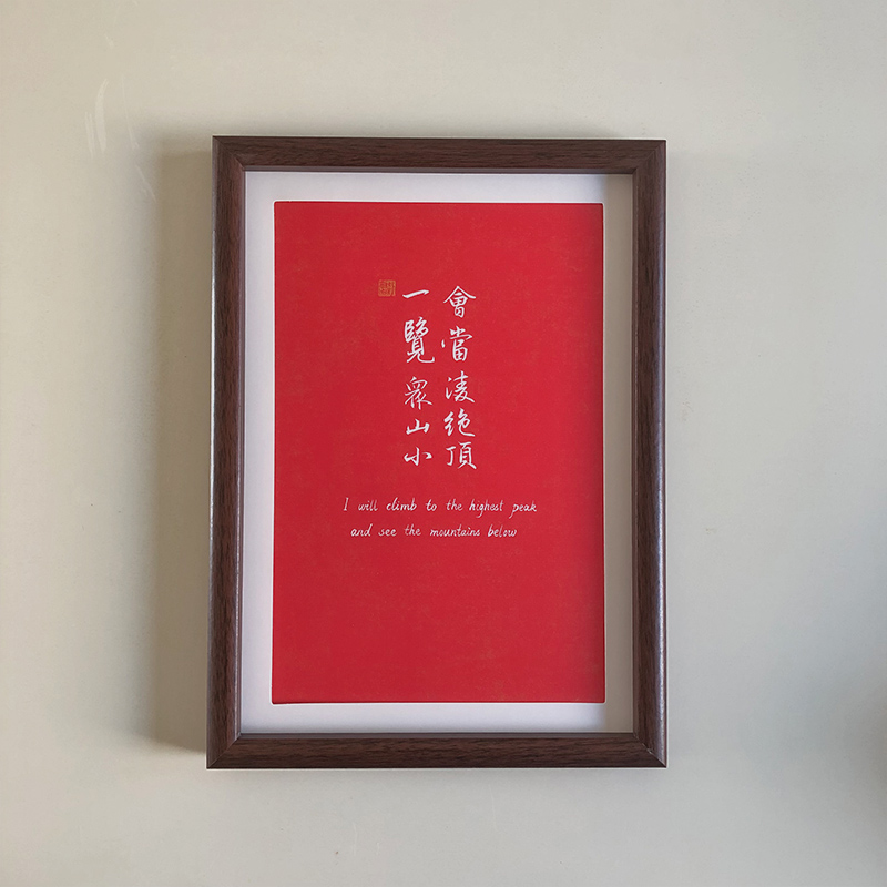 A4 framed red paper Chinese calligraphy art print with dark wood frame hanging on wall