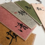 Close-up angled view of stacked handwritten Chinese calligraphy bookmarks showing rich paper textures and brushwork.