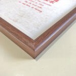 Macro detail of smooth dark walnut wood frame corner for A4 wedding art display
