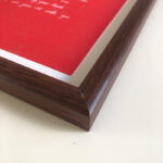 Macro detail of smooth dark walnut wood frame corner framing red paper calligraphy art