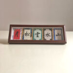 Framed Chinese calligraphy desk art featuring five character characters in traditional silk border.