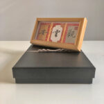 Side perspective view of horizontal natural wood framed Guan Yun An calligraphy display on tabletop