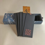 Handwritten Chinese calligraphy blessing bookmark gift set with blue cloud-patterned gift box and black sleeves.
