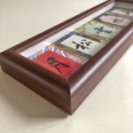 Close-up angled view of solid wood frame with handwritten Chinese ink calligraphy.