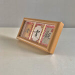 Side perspective view of horizontal natural wood framed Guan Yun An calligraphy display on tabletop
