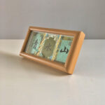 Side perspective view of horizontal natural wood framed Song Brocade calligraphy display on tabletop