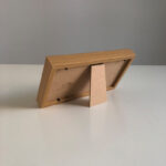 Back view of horizontal wood picture frame showing sturdy easel back stand on tabletop