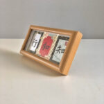 Side perspective view of horizontal natural wood framed handwritten Zhi He Xing calligraphy display on tabletop