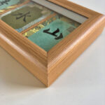 Macro detail of smooth natural wood frame corner showcasing 3 Song Brocade calligraphy panels