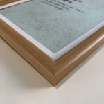 Macro detail of smooth natural wood frame corner framing light green paper calligraphy art
