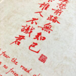 Close-up of red Xingzhuo Chinese calligraphy brush strokes and red seal stamp on textured paper