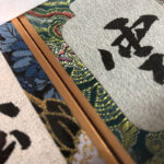 Macro detail of Song Brocade woven fabric trim and handwritten Chinese calligraphy character Cloud.