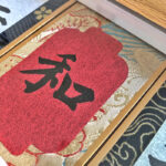 Macro detail of woven Song Brocade silk fabric border and original handwritten Chinese calligraphy ink strokes on red cardstock