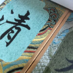 Macro detail of woven Song Brocade silk fabric border with traditional pattern and Chinese calligraphy character Qing