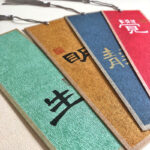 Close-up angled view of stacked colorful Chinese calligraphy bookmarks showing rich paper textures and gold ink brushwork.