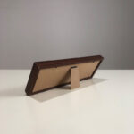 Side angle of calligraphy desk display showing foldable frame stand on white tabletop.
