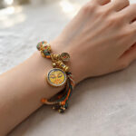 Yellow Manjushri Buddha Eye charm bracelet on model wrist with warm yellow accents.