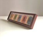 Angled front view of framed Chinese calligraphy desk decor with colorful silk fabric trim.
