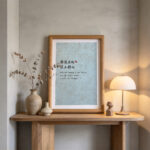 Light oamony on a wooden console table beside dried botanicals and a warm lamp.k framed sage green Chinese calligraphy print reading Qin Se In Har